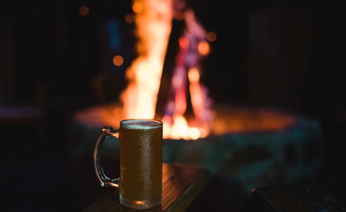 Friends enjoying craft beer by a fire pit at D&D Brewery